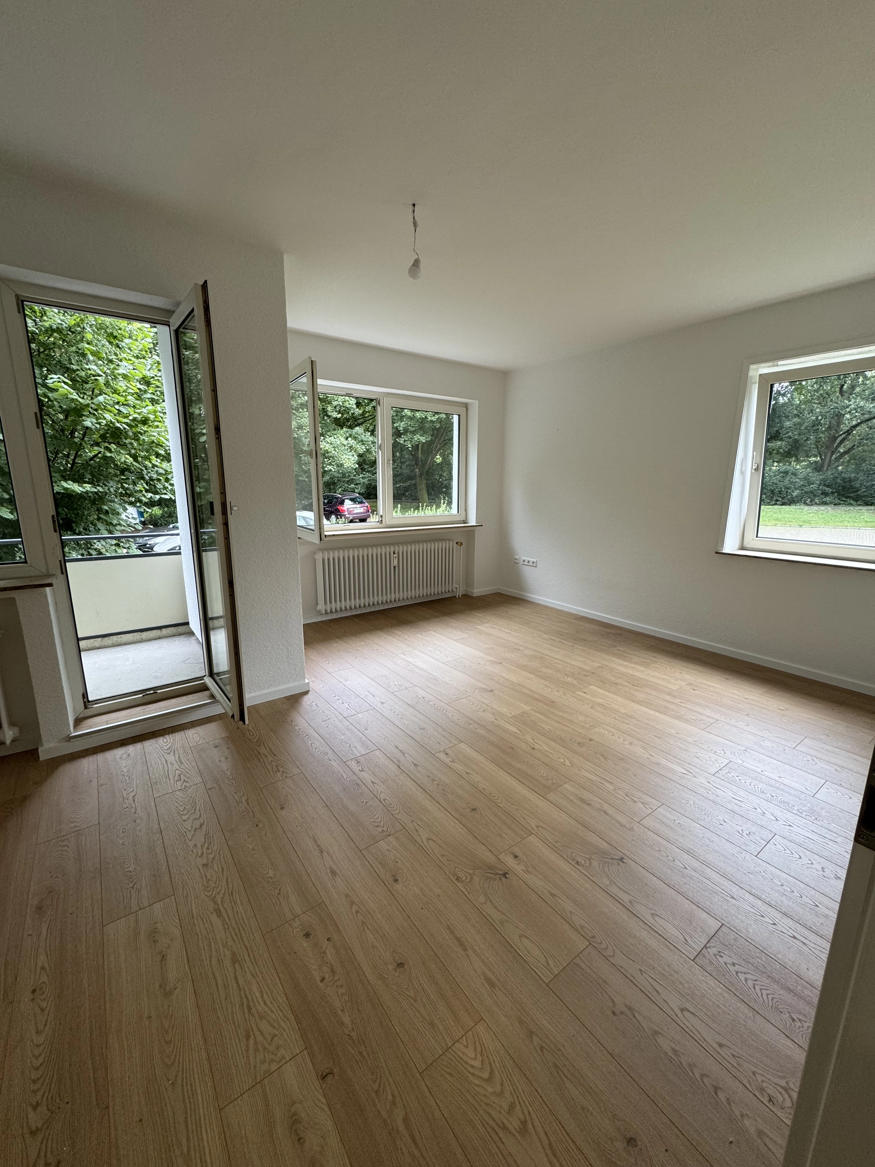 Wohnzimmer mit Balkon, viel Licht und Grün