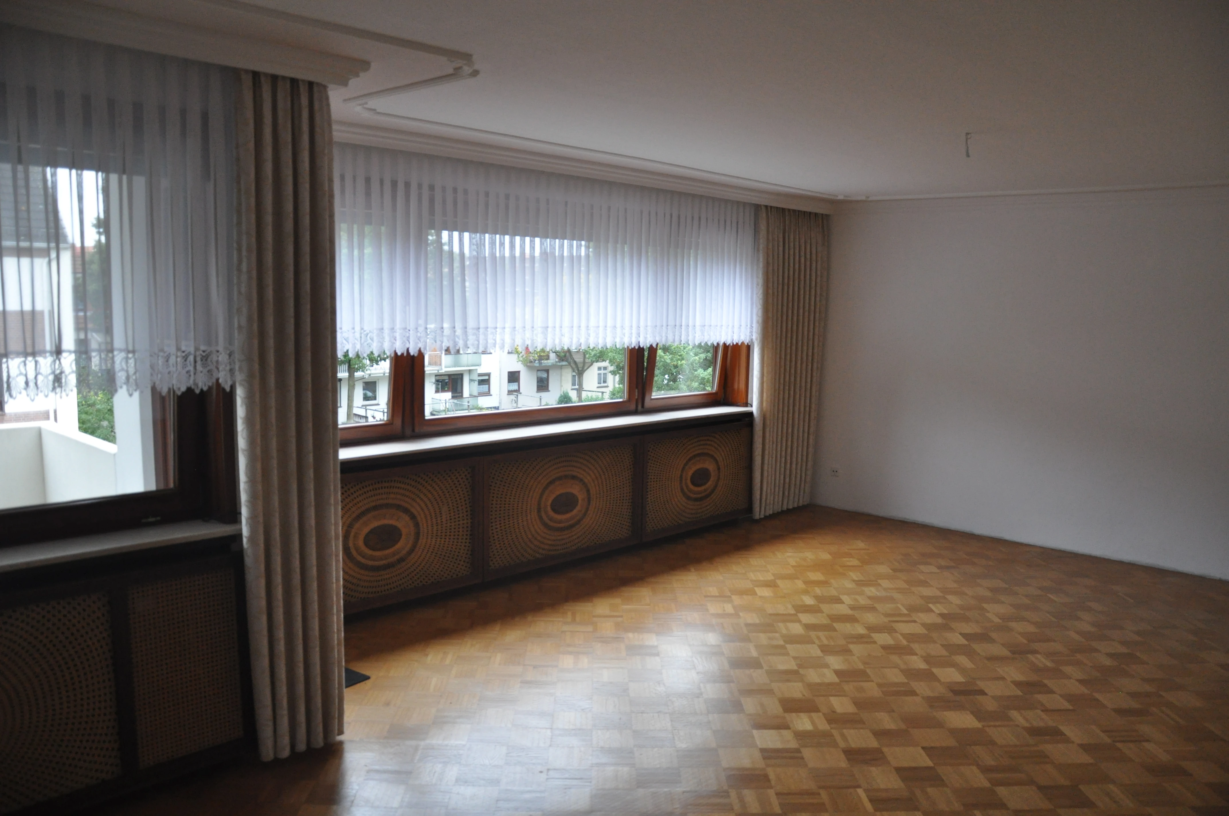Wohnzimmer, Aufnahme alt, heute ohne Gardinen, mit weißen Heizkörperverkleidungen