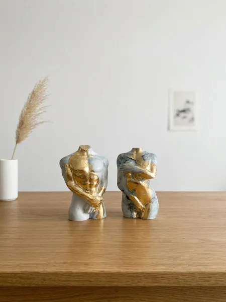 Skulpturen von weiblichen und männlichen Torsos in Marmoroptik mit edlen Blattgold-Akzenten